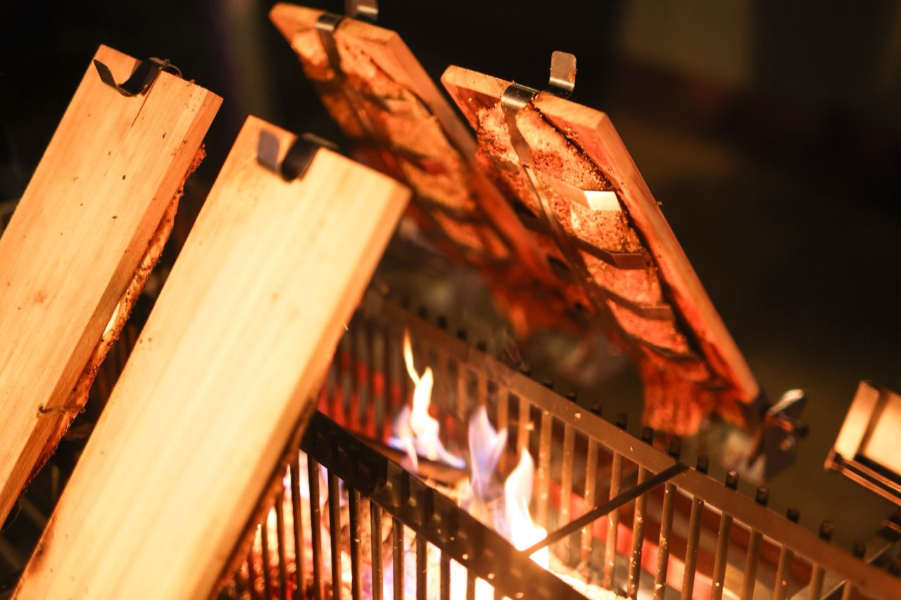 Lachsseiten auf Holzbrettern direkt an den Flammen