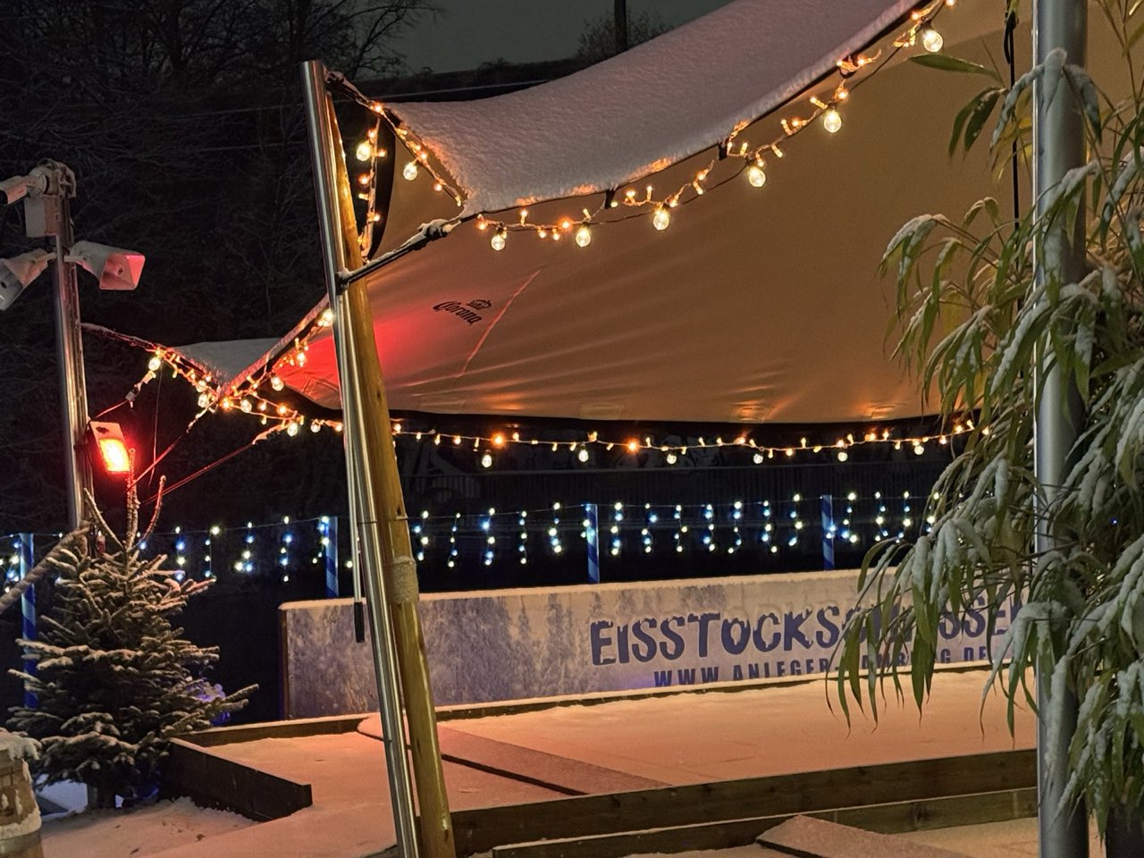 Eisstockbahn im Schnee unter dem Segel mit Lichterketten