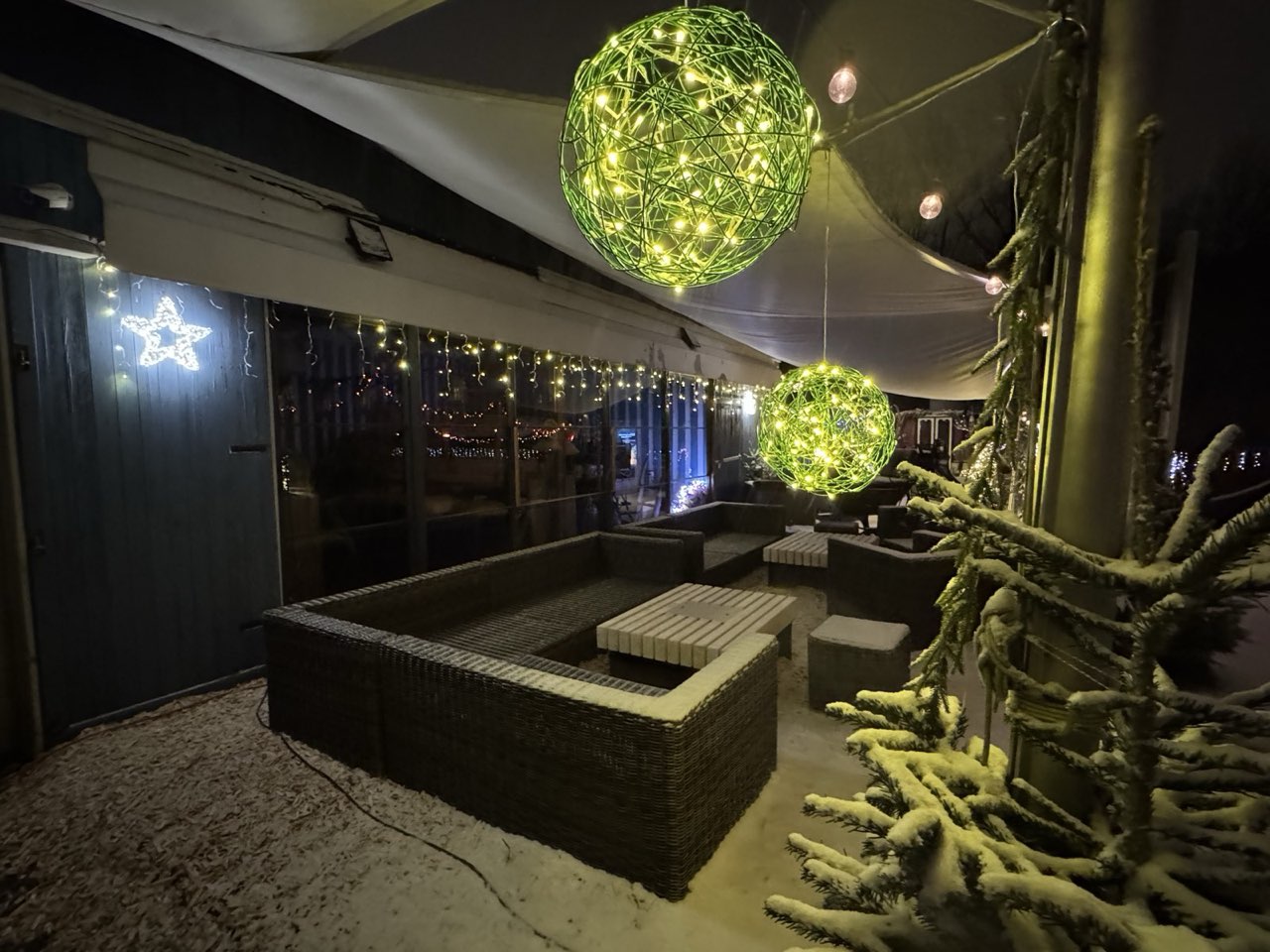 Verschneite Lounge unter dem Segel mit grün leuchtenden Lichtkugeln
