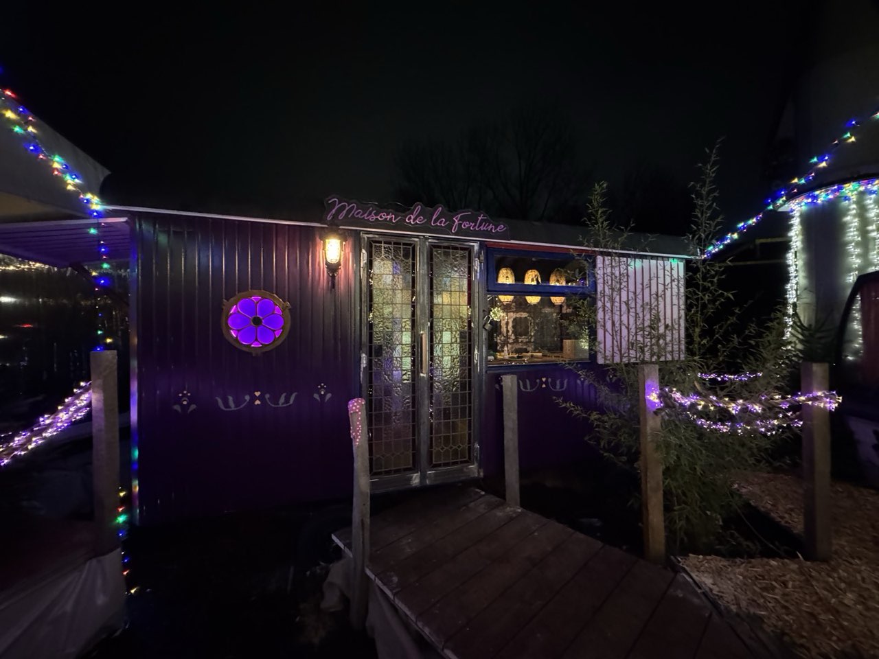 Der violette Wahrsagerwagen bei Nacht mit Leuchtschrift und Lichterketten