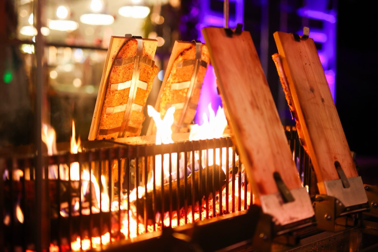 Lachsseiten auf Holzbrettern am offenen Feuer