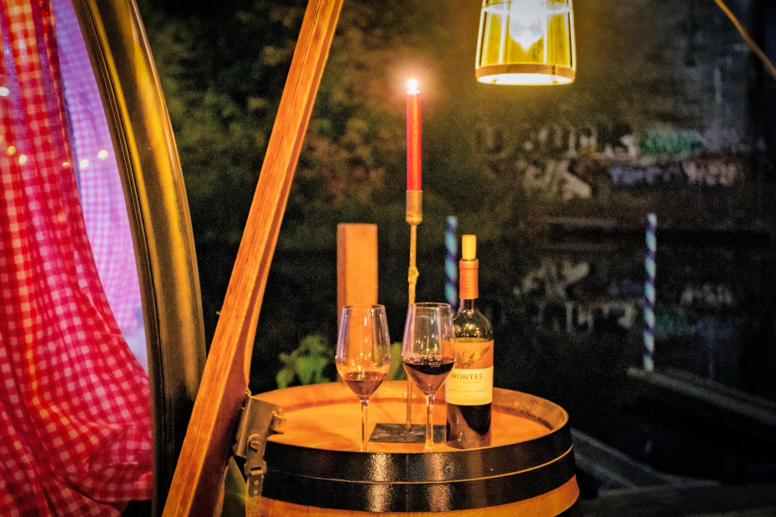 Zwei Gläser Rotwein und eine Kerze auf einem Weinfass neben der Gondel, dahinter das Wasser